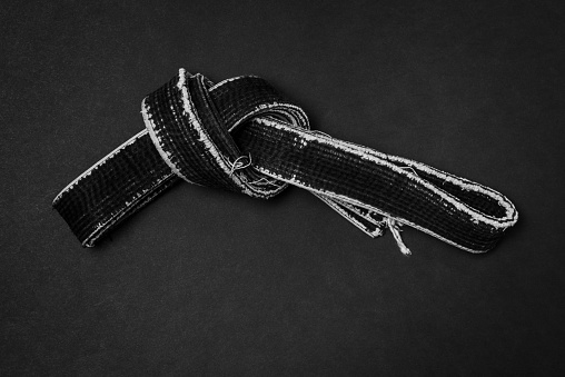 Martial arts  black shabby master's belt on a black background.