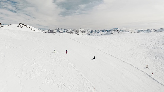 Livigno, Italy - February 21, 2022: People snowboarding skiing at ski resort. Skiers, snowboarders riding snowy mountain slope. Outdoor winter sport, scineric panoramic view.