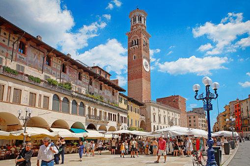 Bridge Ponte Pietra in Verona on Adige river. Veneto region. Italy. Sunny summer day panorama and blue sky with clouds. Ancient european terracotta color houses