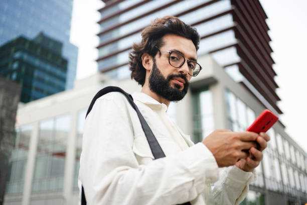 istock Young man with eyeglasses and beard using phone outdoors in the city 1783510131