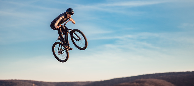 Young man flying through the air on a mountain bike