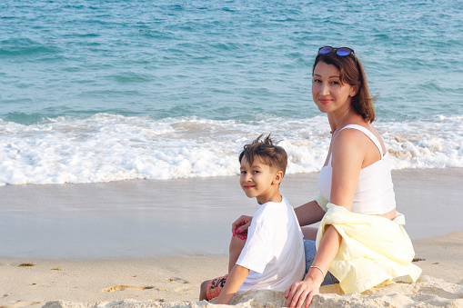 Mother and son sitting on sandy beach