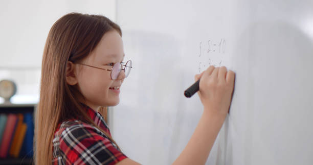 istock Child writing solution of mathematical operation on board in classroom. 1783538953