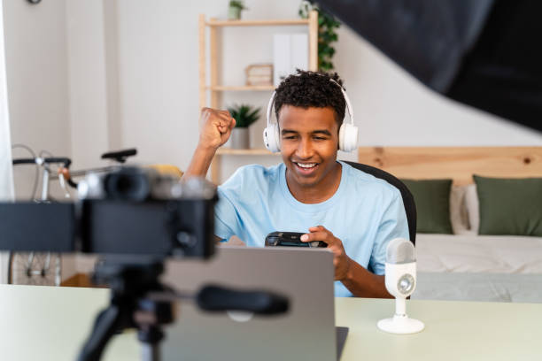 Streamer streaming video game online with victory gesture.
