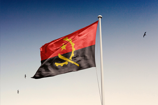 La bandera de Angola ondeando en el viento en el cielo. photo