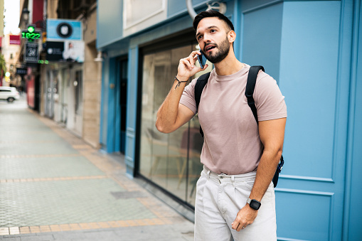 Portrait of a young gay man talking on mobile phone on the street.