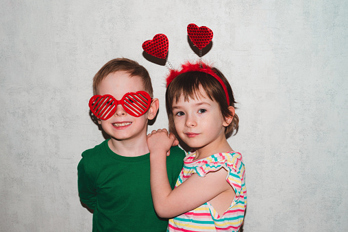 Couple of children are having fun hugging. Boy and girl wearing accessories for Valentine's day. Holiday and fun concept.
