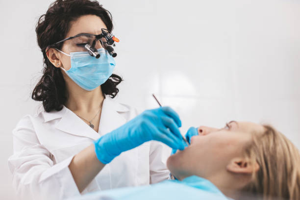 istock Female dentist examining patient's mouth using stomatological binoculars. 1783559188
