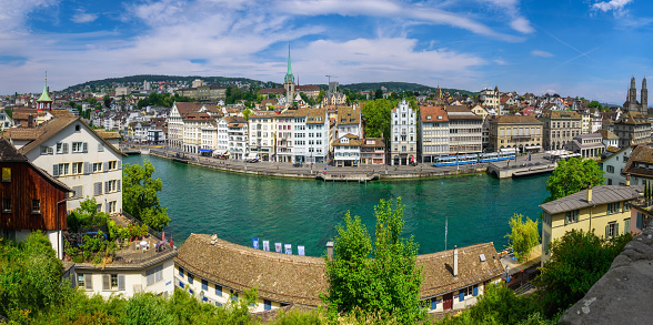 Zurich, Switzerland - June 18, 2023: Cityscape of downtown Zurich with Limmat river embankment on a clear sunny day with blue sky. Panoramic view.