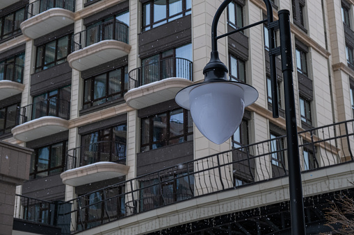 Lantern on the background of a residential building. It's snowing.