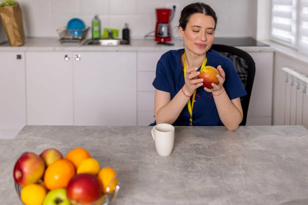 istock Young female nurse cheerfully enjoying her coffee break, while holding an apple in her hands 1783565927