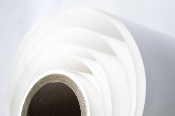 White polygraph paper on a cardboard core. A bundle of leftover paper in a printing house. Material for the printing industry. Selective focus