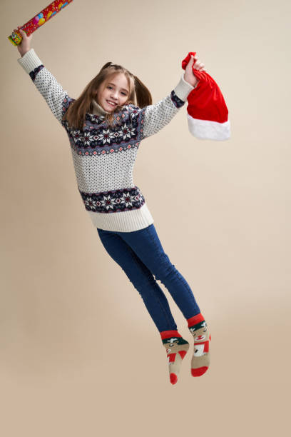 Young girl in blue jeans and sweater jumps on beige background stock photo