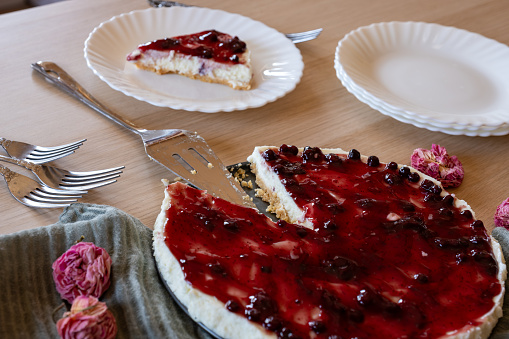 Cold cheesecake with cherry jelly served on wooden table with forks flowers roses and green veil