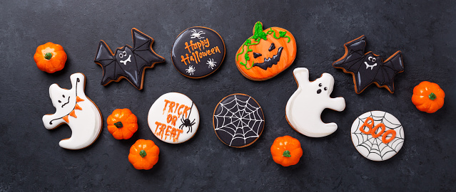 Halloween banner with gingerbread cookies on dark stone background. Bright homemade cookies for Halloween party