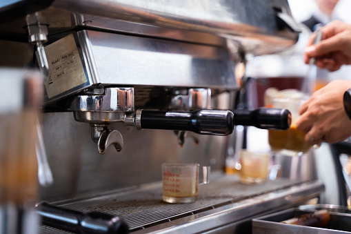 The barista makes latte art coffee with an espresso machine.