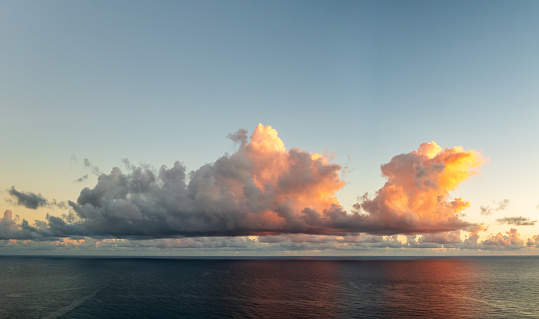 Panorama of sunlit cumulus clouds over ocean horizon on Kauai