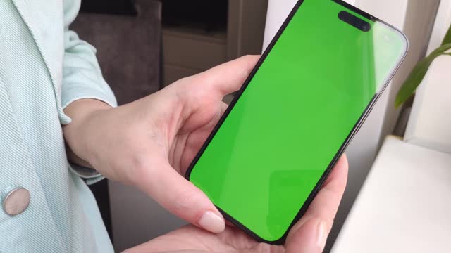 a woman scrolls the tape into a smartphone and shows it to the camera, a smartphone with a green screen close-up