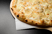 Delicious creamy sauce pizza Quattro formaggi with four kinds of cheese on black background