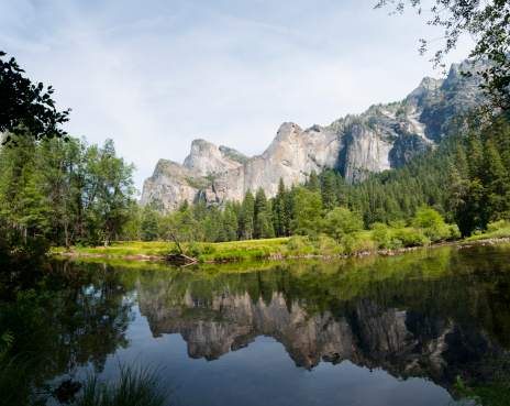 Panoramic view of the 3 Sisters in Yosemite National Park with their reflection on the water.