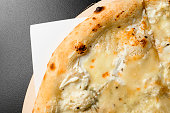 Appetizing view on white pizza Quattro Formaggi with cheddar, parmesan, mozzarella and blue cheese on black background