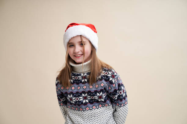 Girl in Santa's hat and sweater smiles stock photo