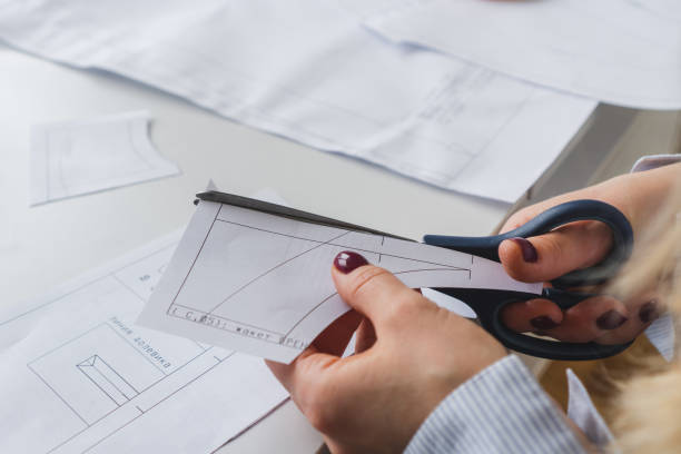 istock Seamstress cuts papper patterns for dress with scissors. Design development and clothes creating 1783618945