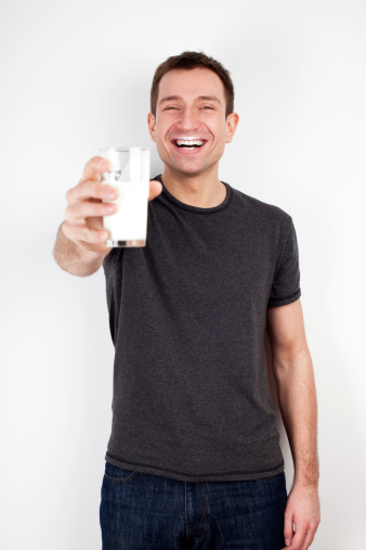 Young man smiling with glass of milk. Isolated