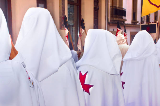 Historical reenactment, rear view of row of templar knights with hoods. Medieval Festival ,period clothings, parade along the street.  Mondoñedo medieval historical reenactment. Lugo province, Galicia, Spain.