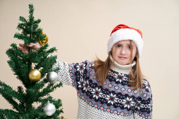 Girl with cute and funny expression holds Christmas tree stock photo