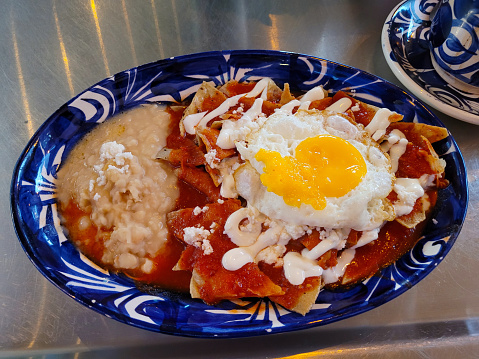 Aerial view of some chilaquiles with fried eggs and beans in a traditional plate