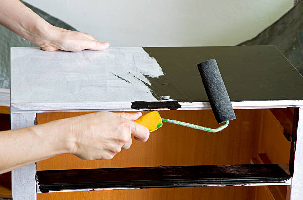 painter with paint roller painter with paint roller painting a wooden commode dresser stock pictures, royalty-free photos & images