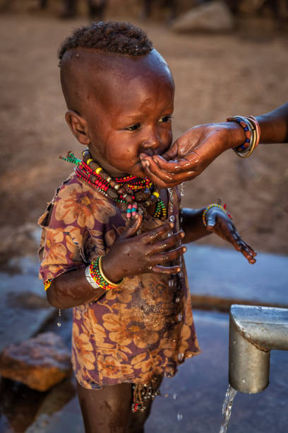 niña africana bebiendo agua de la bomba de agua de mano, etiopía, áfrica - baby child poverty water fotografías e imágenes de stock