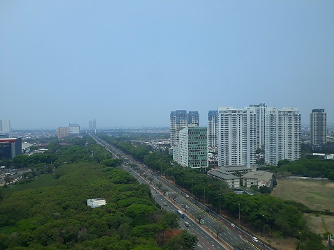 high angle view of the highway and buildings with tree urban gardens in the middle of the city from inside a building in Jakarta