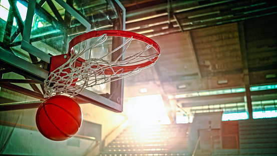 Close-up of basketball falling from basketball hoop in stadium.