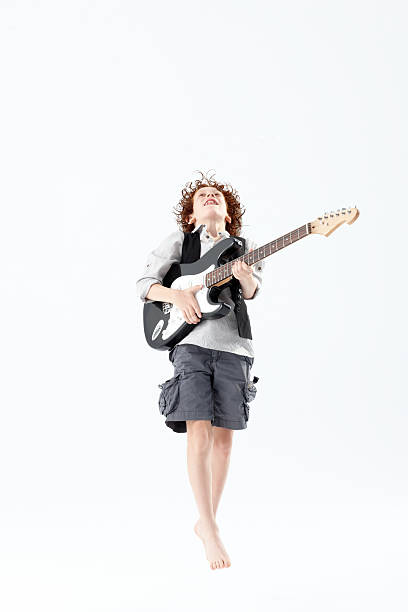 Boy playing electric guitar Eight year old boy jumps while playing an electric guitar rockabilly boys stock pictures, royalty-free photos & images