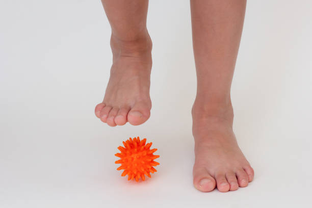 Cropped child legs doing exercises with spiky needle ball
