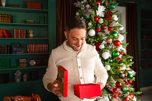 Smiling man opening Christmas present gift box