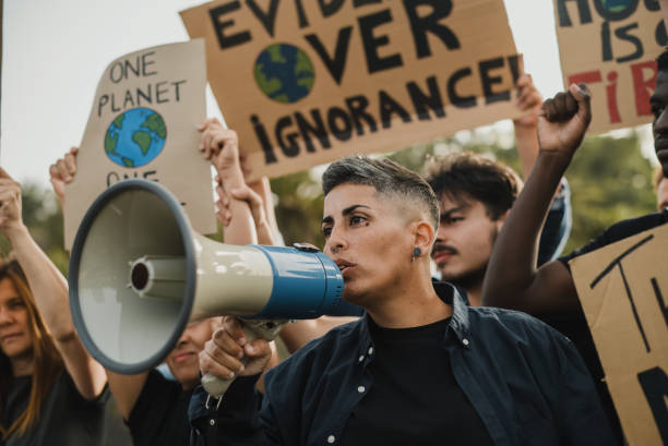 istock Crowd of determined multiracial protesters in casual clothes standing behind leader with megaphone and holding carton placards 1783661995