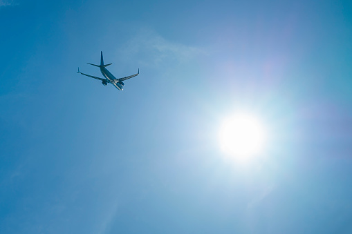 the plane is flying against a background of blue sky and sun