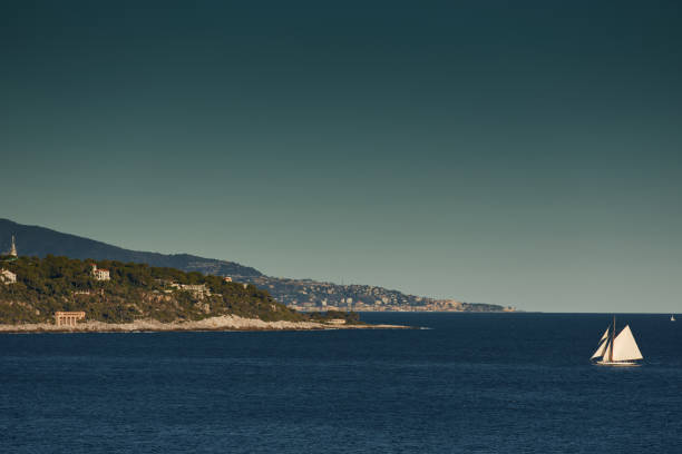 monaco, huge sail yacht is in sea at sunset, island is nearby, wealth life of billionaires, mountains on background - sailing light wind nautical vessel imagens e fotografias de stock