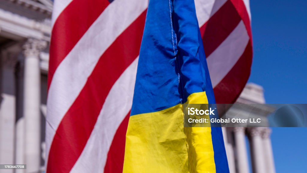 Close up of US, Ukraine flags overlapping each other with capitol building in background on a sunny day American Flag Stock Photo