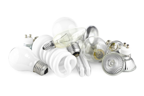 Mixed heap of light bulbs with filament bulbs and energy salving lamps on white.