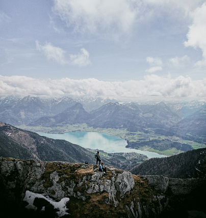 A couple of hikers admire the view of the wolfgangsee in austrian alps.