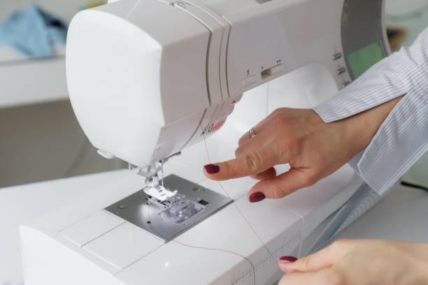 istock Seamstress prepare sewing machine. Tailor puts needle and spool of thread in sewing machine. Closeup 1783671104