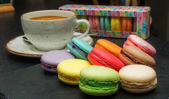 Multicolored macaroons and a cup of tea on the bar counter