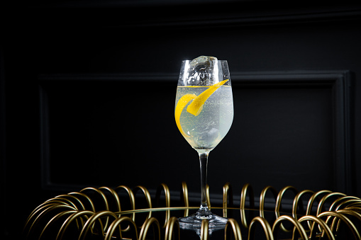 side view of transparent carbonated cocktail with lemon and ice