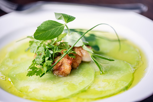 Dish of, panfried scallops, thinly sliced kohlrabi, served with buttermilk sauce with a dressing of chive and honey infused oil. Colour, horizontal format with some copy space. Photographed on location in a restaurant on the island of Moen in Denmark.