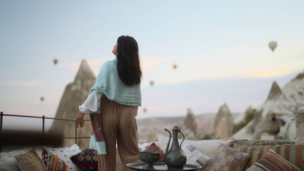 retrato de jovem turista feminina assistindo balões de ar quente da varanda na capadócia durante sua viagem - traditional festival adventure air air vehicle - fotografias e filmes do acervo
