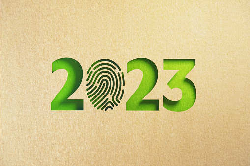 Cut out fingerprint shape made of recycled paper forming 2023 on green background. Horizontal composition with copy space. Sustainability concept.
